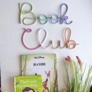 pastel book club sign above cozy kids reading nook with books