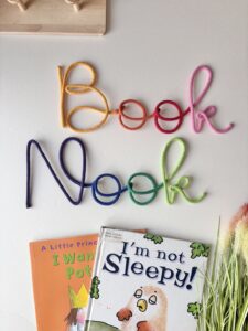 Rainbow Book Nook wall sign above kids reading corner with books