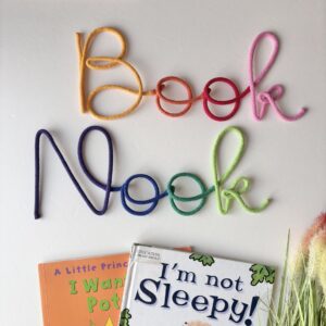 Rainbow Book Nook wall sign above kids reading corner with books