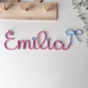 Personalized baby name sign with bow in soft pastel colors displayed in nursery