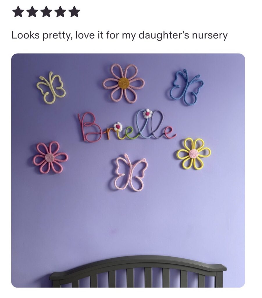 multicoloured name sign with flowers displayed above the bed in girly room