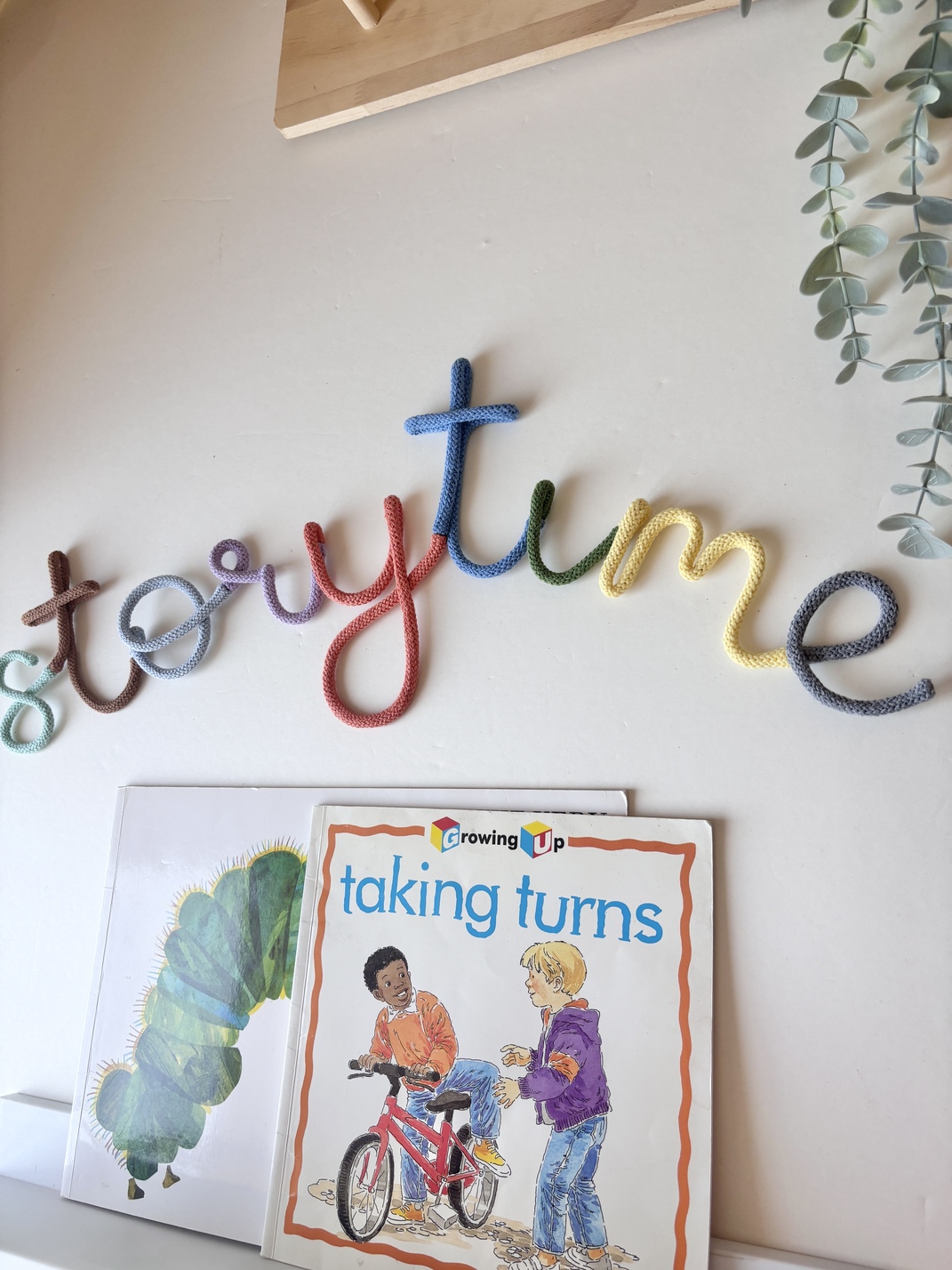 Rainbow Storytime wall sign displayed above a bookshelf, creating a cosy reading nook for children.
