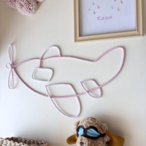 pink airplane wall decor with baby girl's name hanging in a neutral nursery.