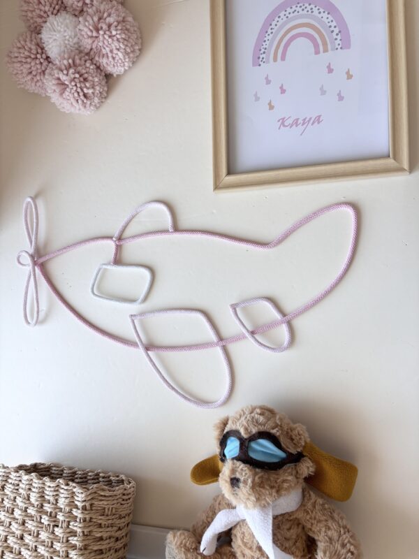 pink airplane wall decor with baby girl's name hanging in a neutral nursery.
