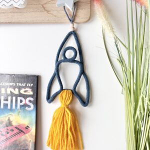 Handmade blue space rocket wall decor for a child's bedroom, featuring a golden tassel.